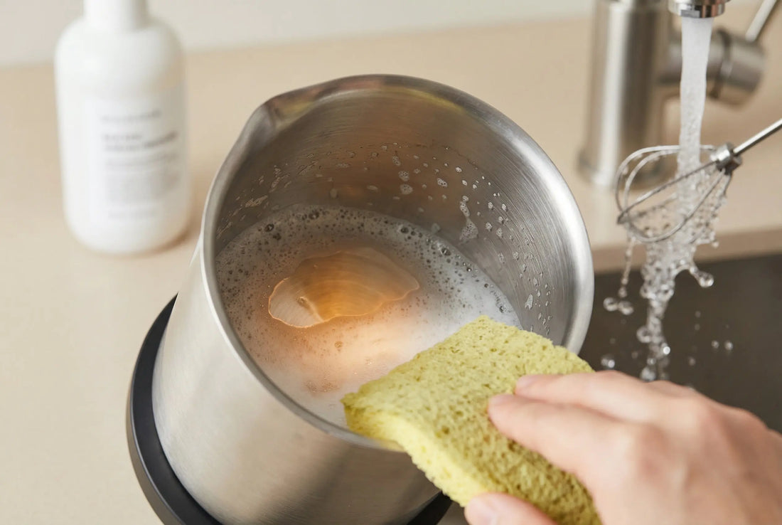Electric milk frother being cleaned with sponge and vinegar