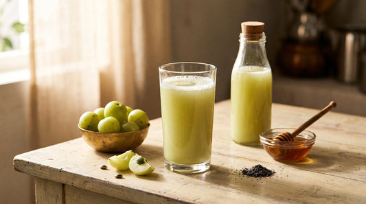Glass of fresh homemade amla juice with whole amla, cut amla, honey and black salt on a wooden kitchen table