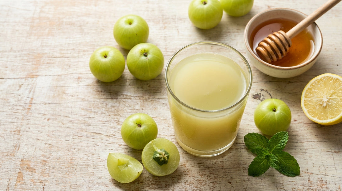 Fresh amla (Indian gooseberry) juice in a glass with whole amla, honey, lemon and mint