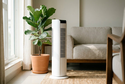White tower air purifier in a bright living room beside an indoor plant and sofa