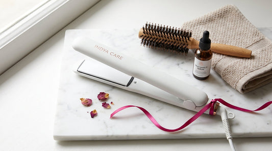 Ceramic hair straightener on a marble vanity with a brush, heat serum and towel