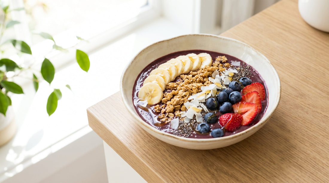 Purple acai smoothie bowl topped with fresh berries banana slices and granola in an Indian kitchen