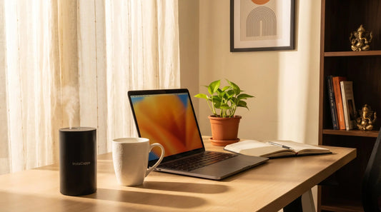 InstaCuppa aroma diffuser on a clean office desk with laptop, coffee mug, and plant — warm afternoon light