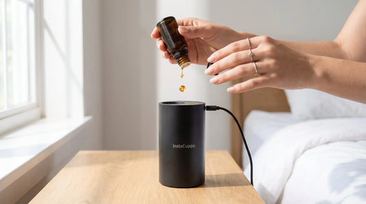 How to use an aroma oil diffuser - hands dropping essential oil into InstaCuppa diffuser on bedside table
