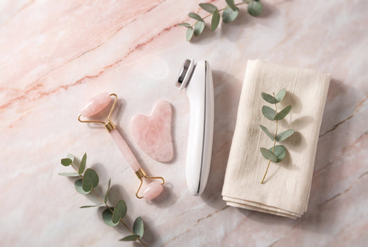 Best facial massager in India 2026 — rose quartz face roller, gua sha stone and electric facial massager on a marble vanity