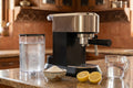 Espresso machine with citric acid powder, lemon, and descaling supplies on Indian kitchen counter