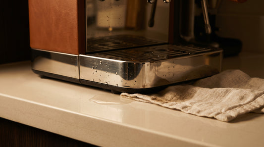 Close-up of espresso machine with water droplets near base showing water leak issue
