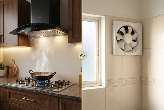 Kitchen chimney over a gas hob with frying steam next to a white wall exhaust fan in an Indian kitchen