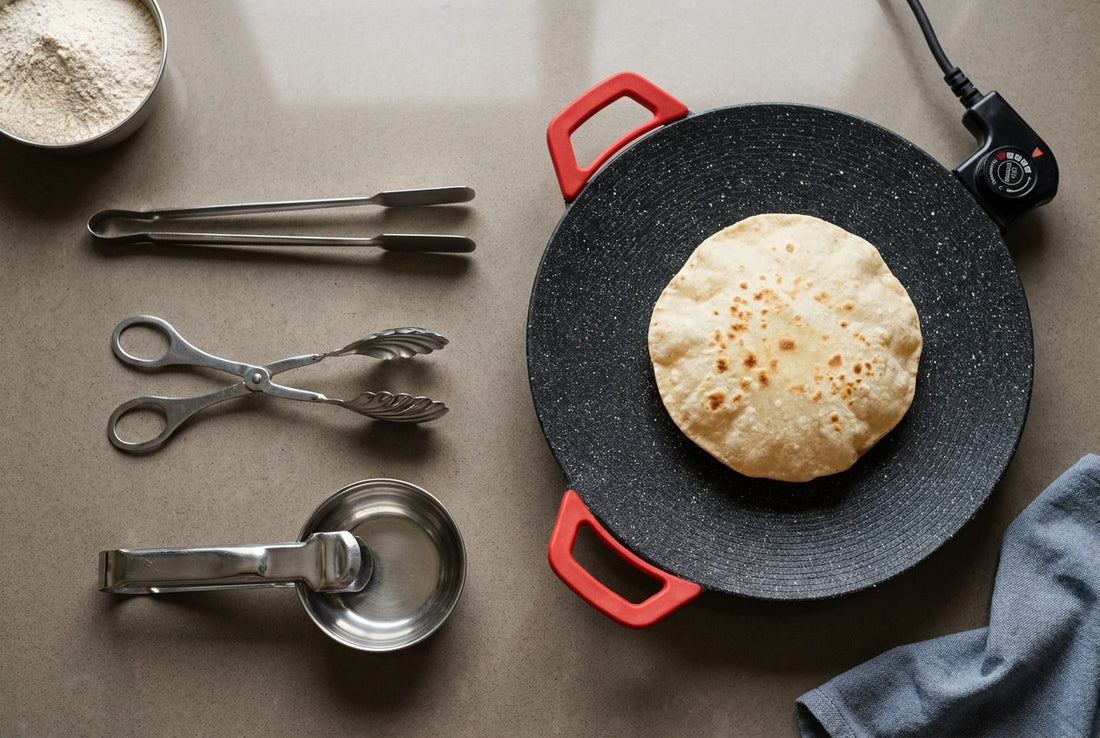 A roti chimta, hinged serving tongs and a utensil pakkad laid beside an InstaCuppa electric non-stick tawa with a roti on it, on an Indian kitchen counter