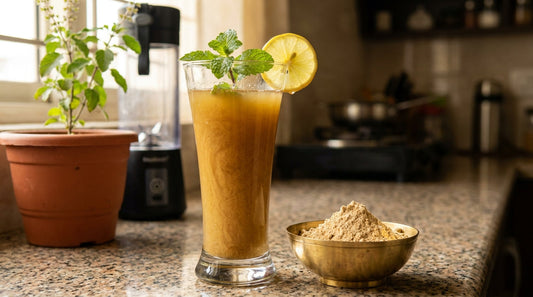 Sattu drink recipe - golden-brown sattu sharbat with mint and lemon garnish next to a bowl of sattu powder in an Indian kitchen