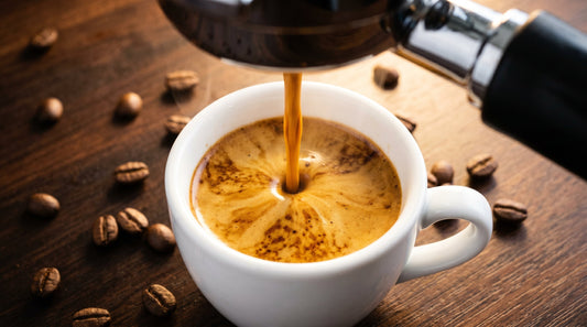 Perfect espresso shot being pulled from a portafilter into a white demitasse cup with golden crema forming on top
