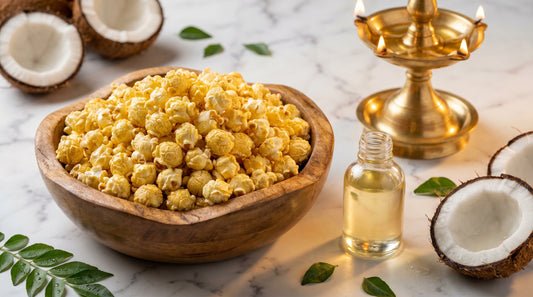 Golden coconut oil popcorn in wooden bowl with coconut halves, curry leaves, and South Indian brass lamp