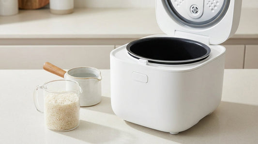 Open electric rice cooker with a measuring cup of basmati rice and a jug of water