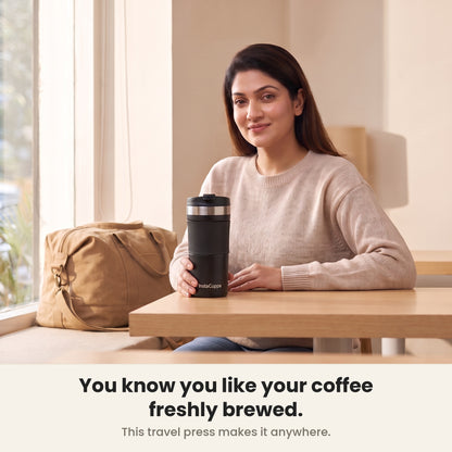 Woman enjoying freshly brewed coffee from her InstaCuppa French Press Travel Mug by a bright window
