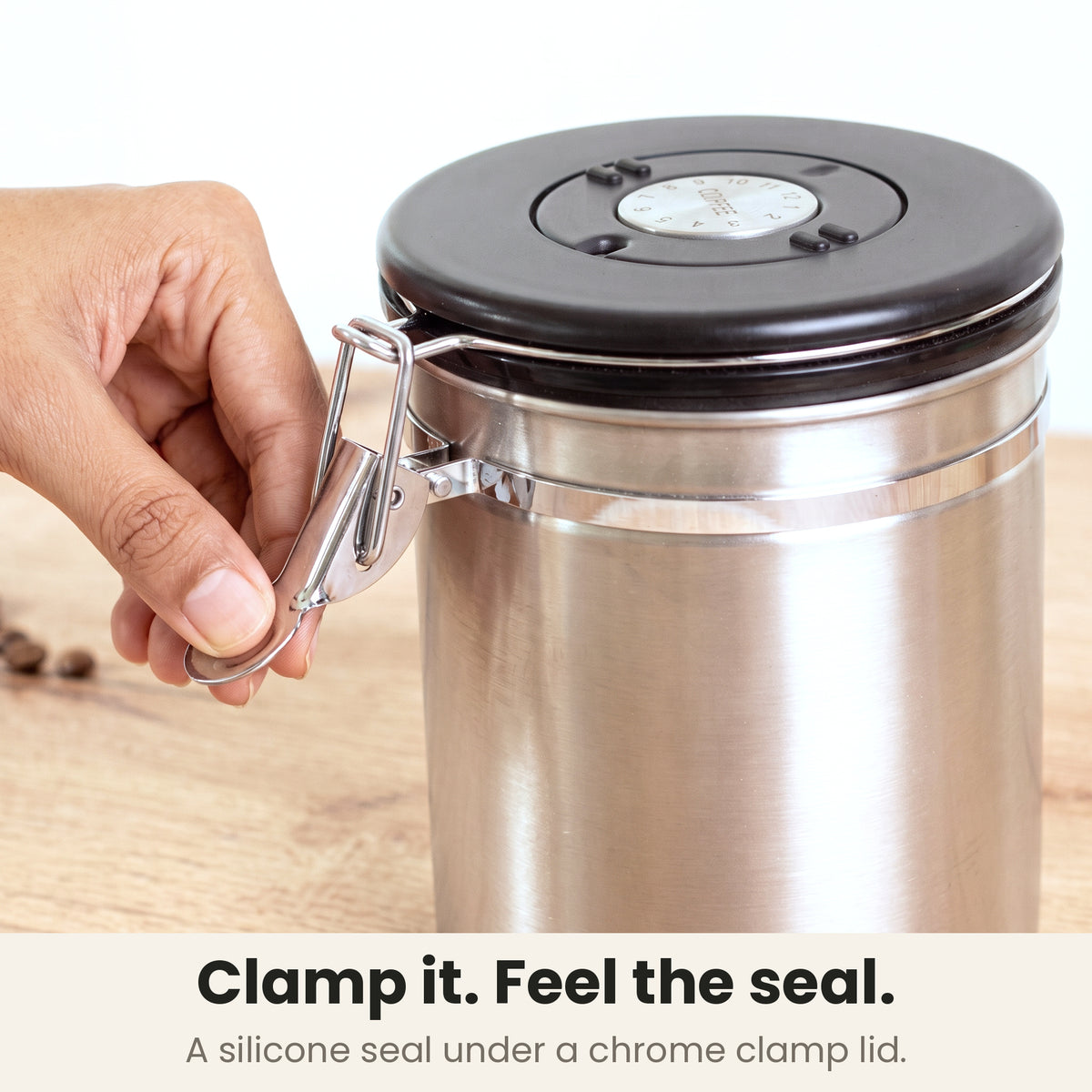 Airtight coffee container - Steel - chrome clamp lid closing on a silicone seal, a hand pressing the clamp shut