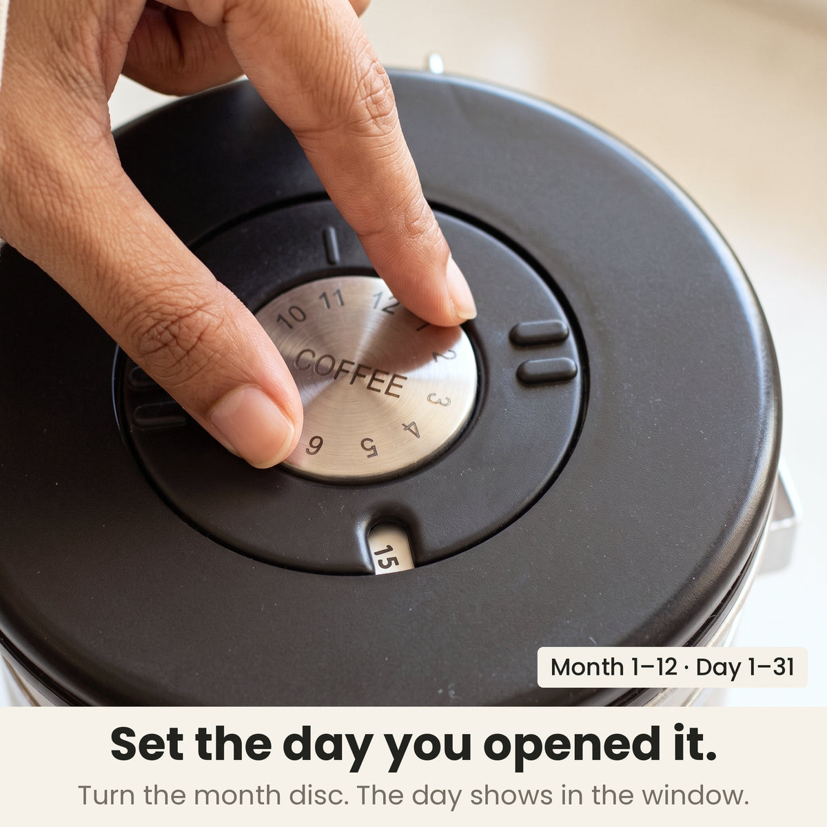Airtight coffee container - Steel - date wheel on the lid, a finger turning the month disc while the day window shows 15