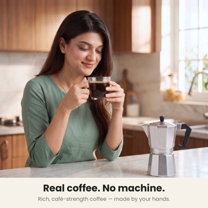 InstaCuppa Aluminium Moka Pot 300 ml - Silver - real coffee, no machine: a woman sipping rich, café-strength coffee with the moka pot on the counter