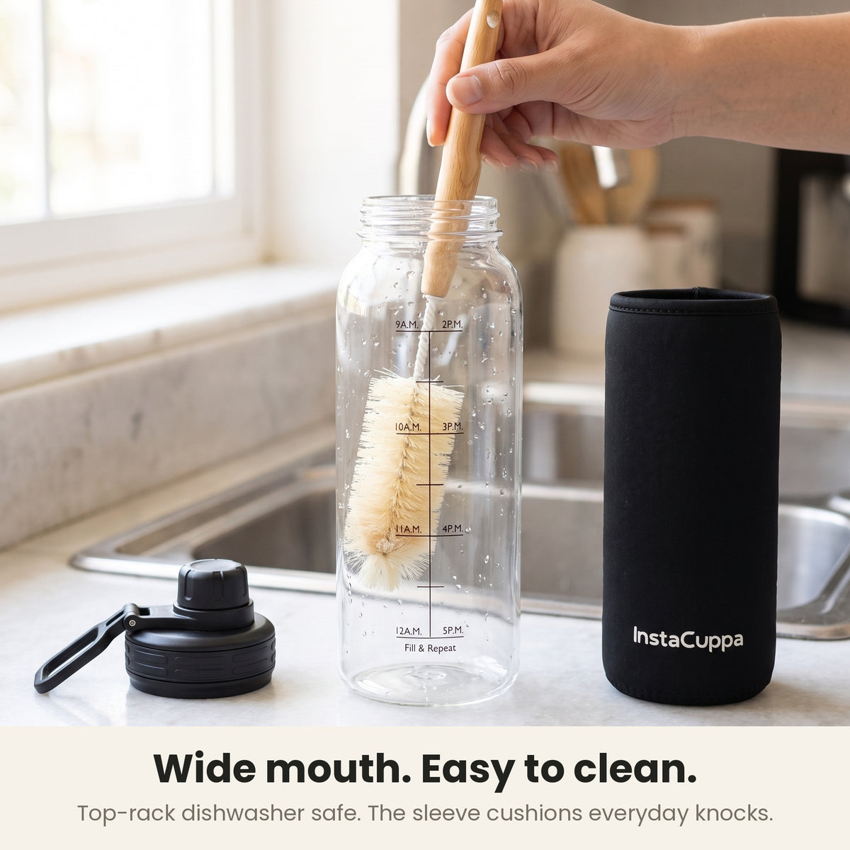 InstaCuppa Borosilicate Glass Water Bottle 1 Litre - Black - wide mouth, easy to clean: a bottle brush in the mouth by the sink, lid and sleeve beside it; top-rack dishwasher safe