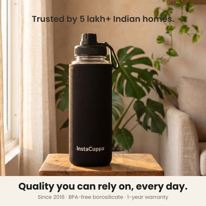 InstaCuppa Borosilicate Glass Water Bottle 1 Litre - Black - on a table by the window