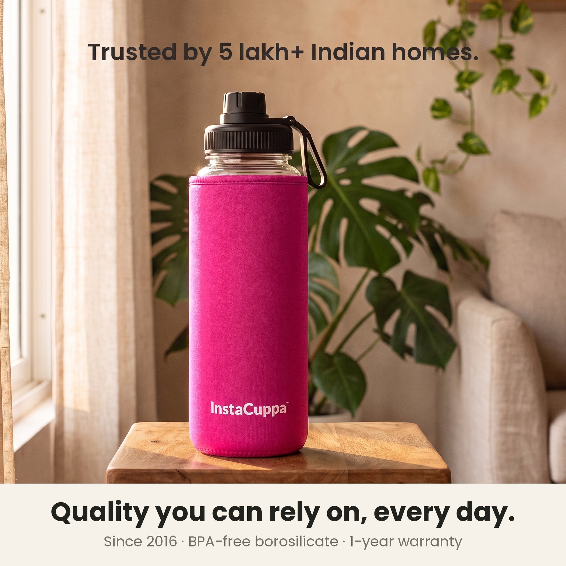 InstaCuppa Borosilicate Glass Water Bottle 1 Litre - Pink - on a table by the window