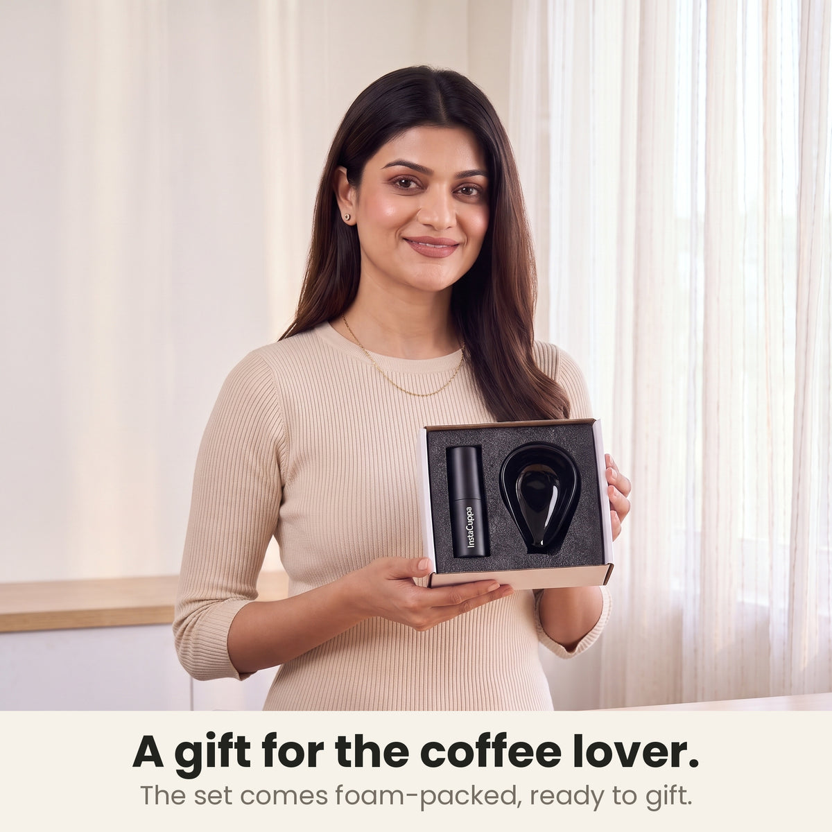 Coffee bean dosing cup and spray bottle gift set, foam-packed and ready to gift, held by a smiling woman in a sunlit room