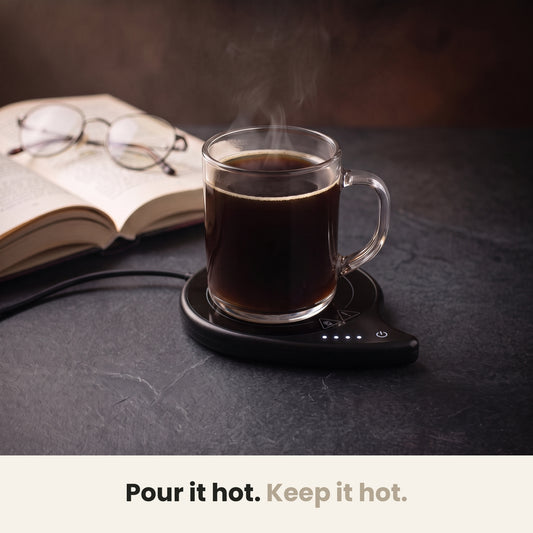 InstaCuppa coffee mug warmer for desk — glass mug of black coffee kept hot on a slate table beside an open book
