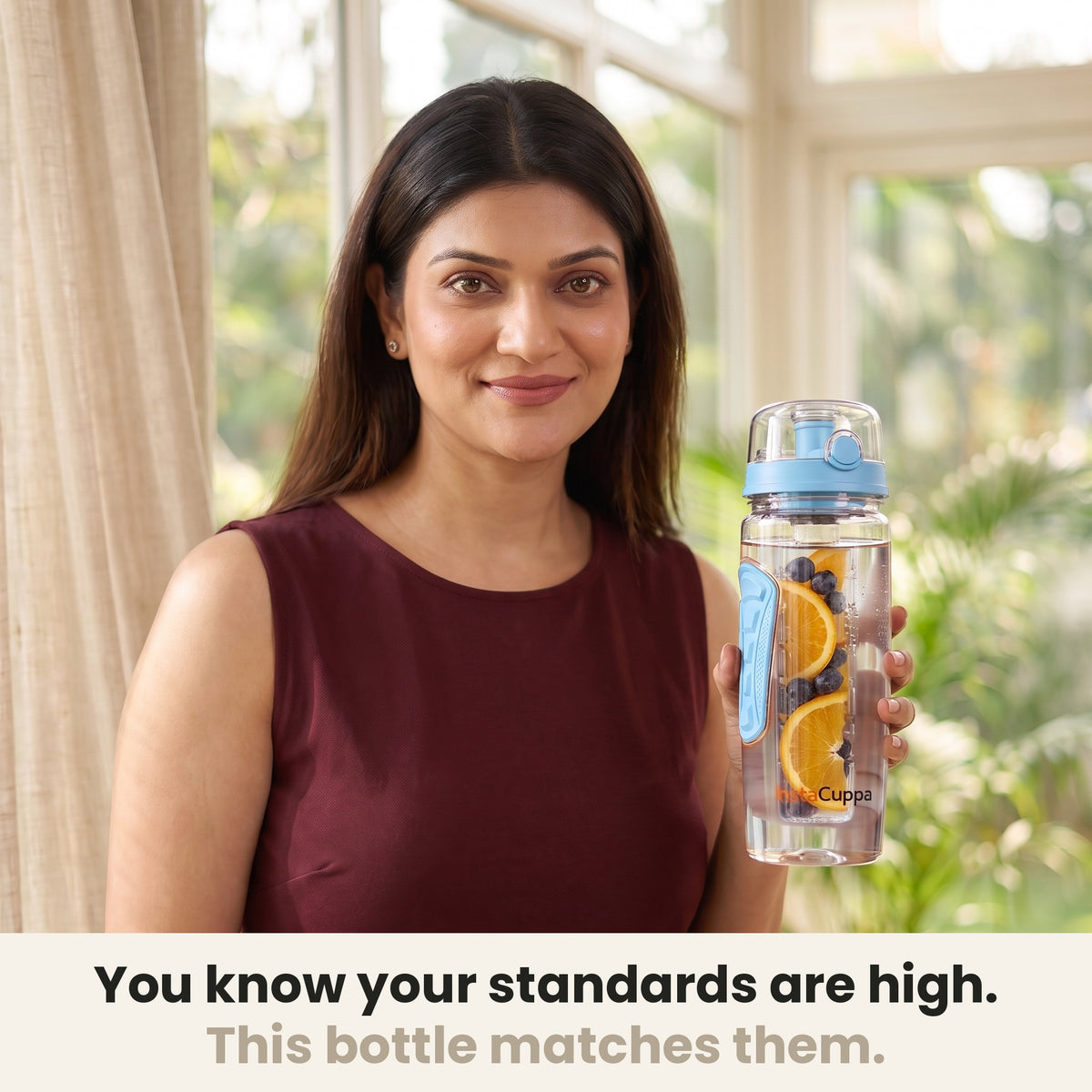 InstaCuppa Fruit Infuser Water Bottle 1 Litre - Blue - woman holding the bottle in a sunlit room, made for your standards