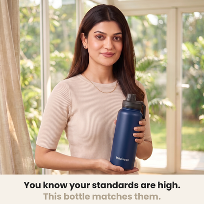 InstaCuppa Insulated Water Bottle 1L (1000 ml) - Navy Blue - woman in a cream ribbed knit top holding the bottle in a sunlit room, caption: you know your standards are high, this bottle matches them
