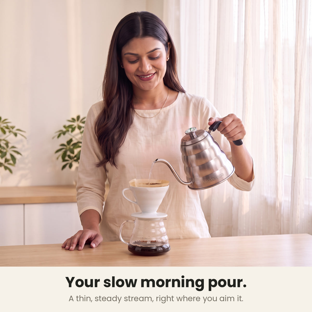 InstaCuppa gooseneck kettle — woman pouring a thin, steady stream onto pour-over coffee in a cone dripper at her kitchen counter