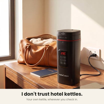 InstaCuppa Portable Electric Kettle 500 ml with Temperature Control - Black - on a hotel desk with travel bag, plugged in